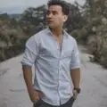 Best Travel Experience A man in casual white shirt and jeans posing confidently on a rural road with trees around.