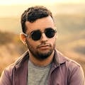 Professional Service A young man with a beard and sunglasses poses confidently outdoors.